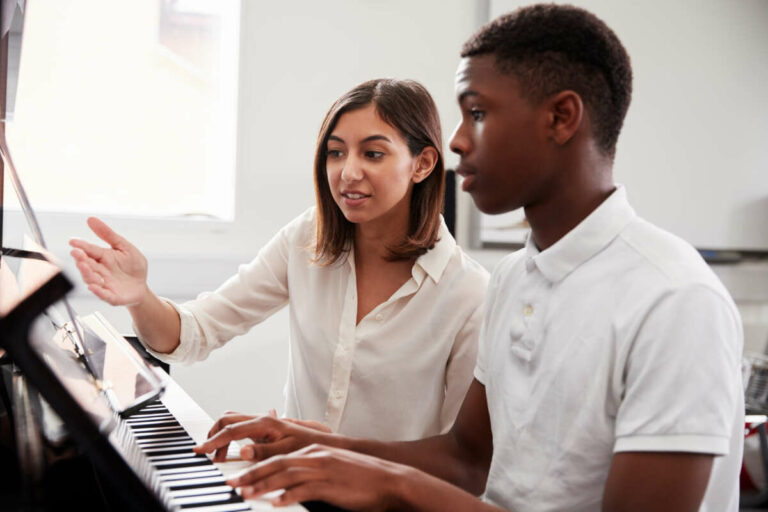 Pupil with teacher, learning piano in a music lesson